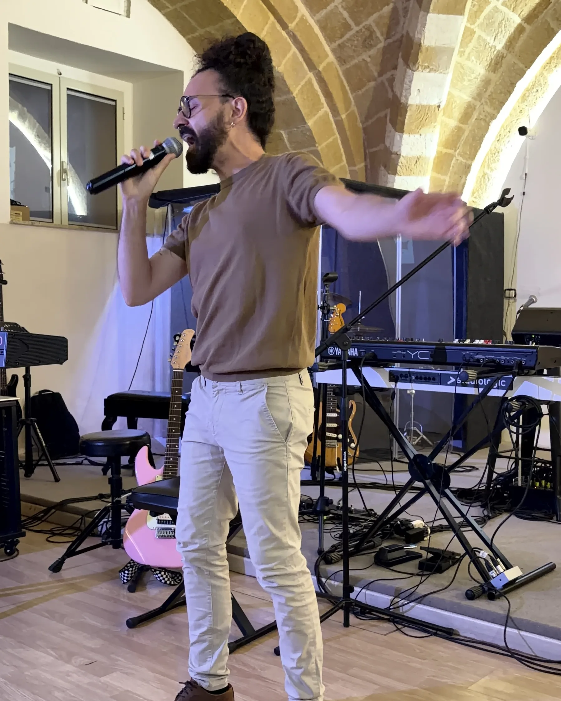 An adult student sings into the microphone at the end-of-year recital, under the stone vaults of Brindisi Tabernacle's center