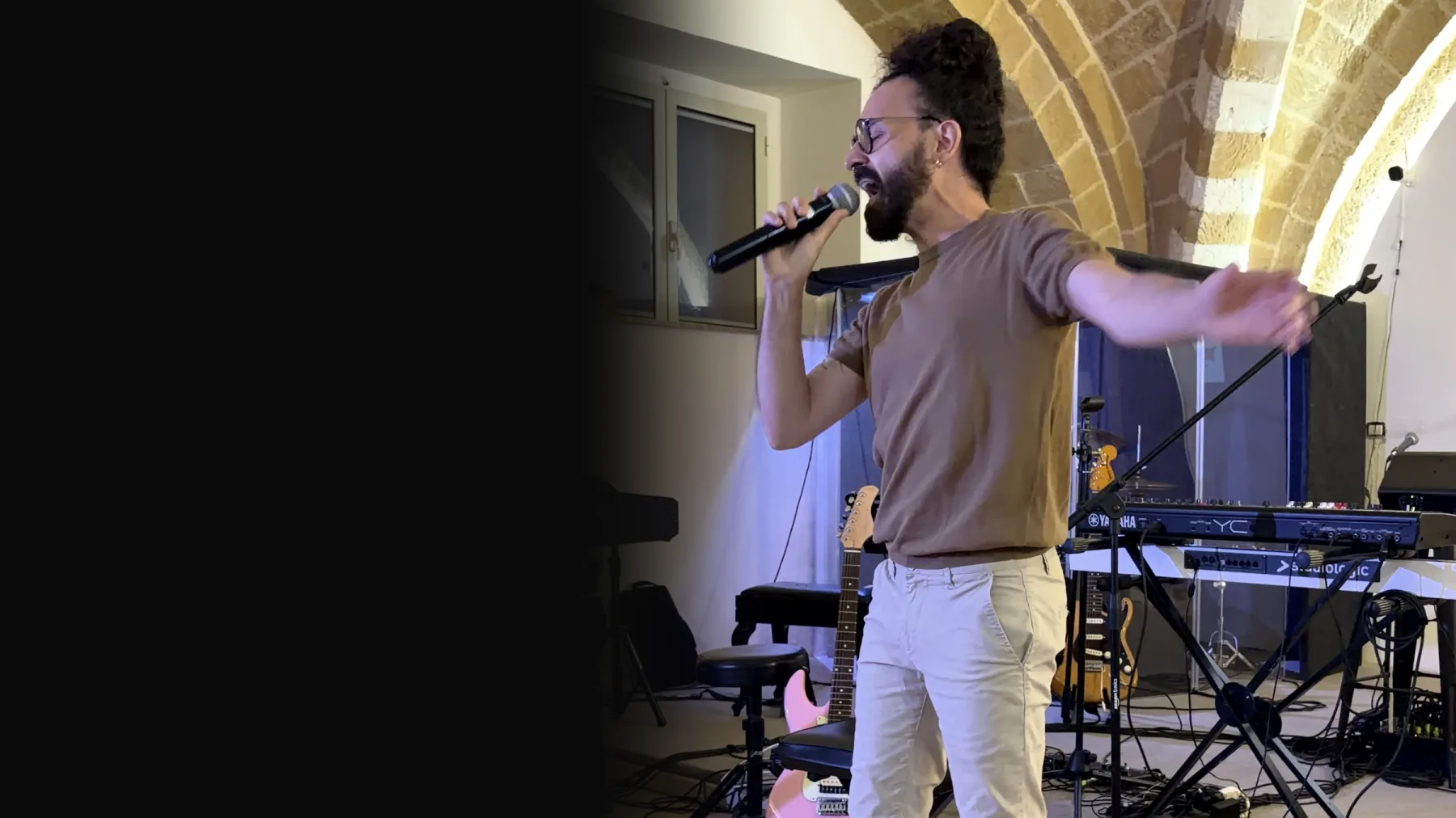 An adult student sings into the microphone at the end-of-year recital, under the stone vaults of Brindisi Tabernacle's center