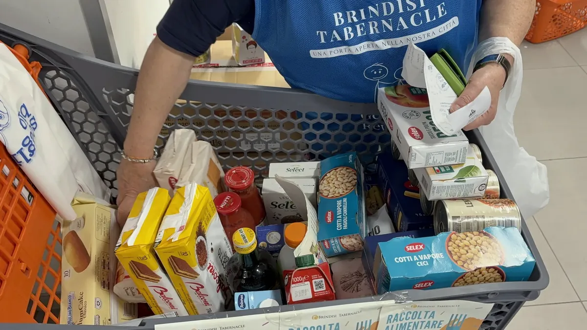 Una volontaria con la pettorina Brindisi Tabernacle riempie un carrello di alimenti donati al supermercato