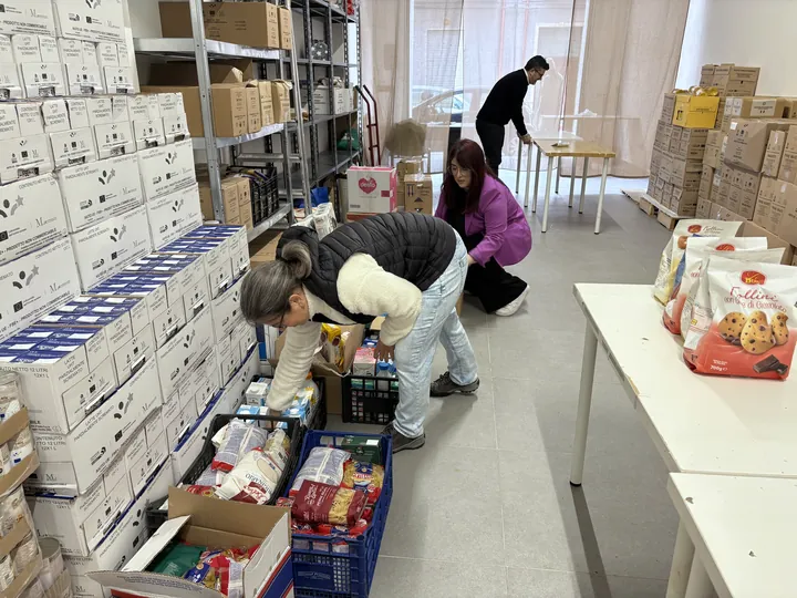 Due volontarie preparano le cassette di alimenti tra gli scaffali del Dream Center