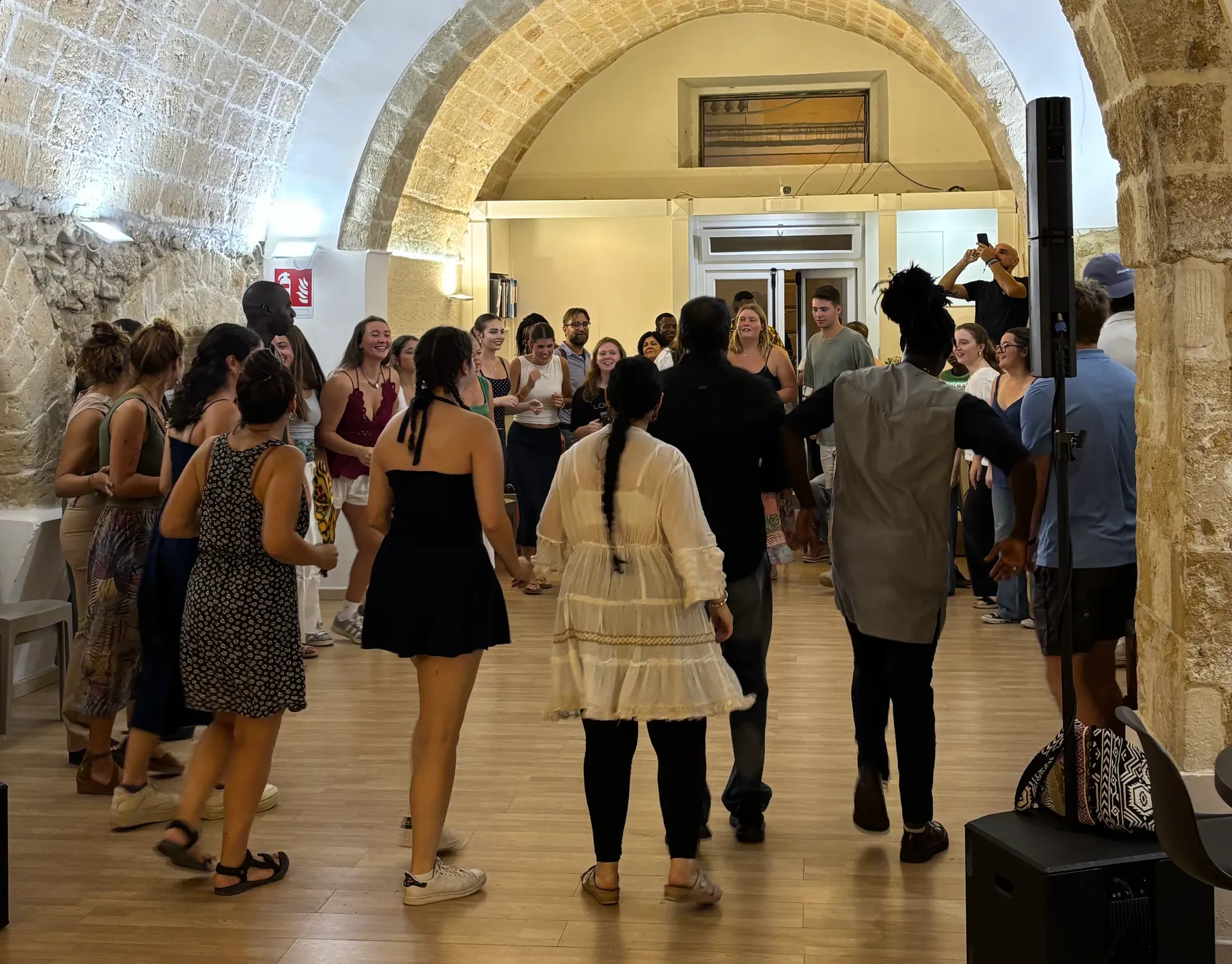 People dancing in a circle under the stone vaults of the centre