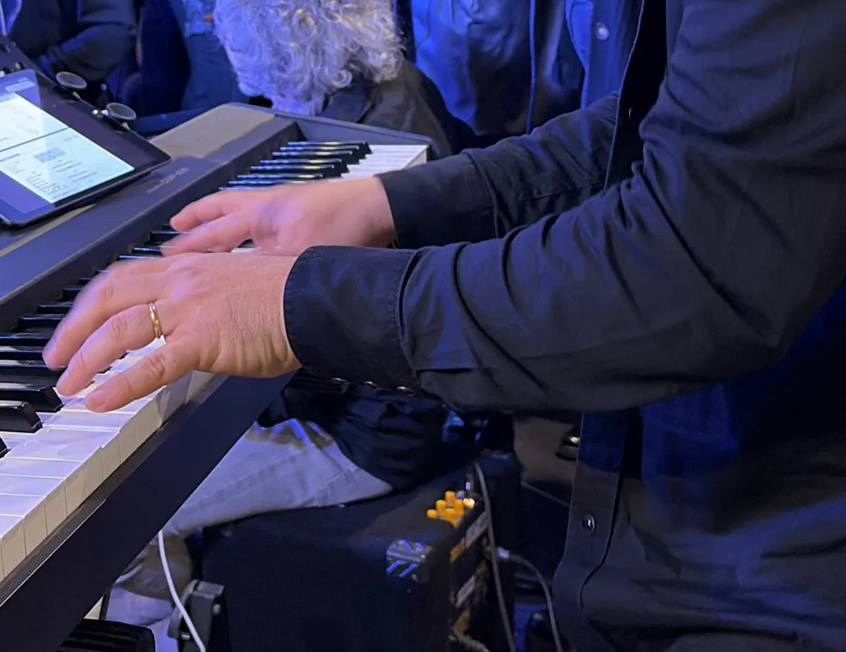 Mani di un musicista adulto sulla tastiera, sotto una luce blu