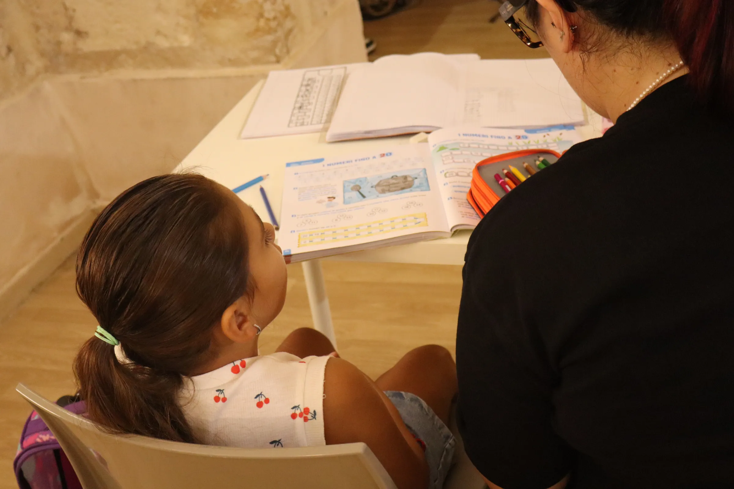A tutor helps a young girl with her maths homework at the after-school club